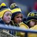 Sydney, 14, Stacey, and Taylor, nine, (left to right) Stites watches their father play and huddle together for warmth during the alumni spring flag football game on Saturday, April 13. AnnArbor.com I Daniel Brenner
